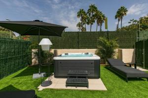 un patio trasero con bañera de hidromasaje y sombrilla en HD Parque Cristobal Gran Canaria en Playa del Inglés
