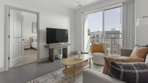 sala de estar con TV, sofá y mesa en Landing - Modern Apartment with Amazing Amenities (ID1398X192), en Richmond