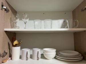a shelf with glasses and plates and wine glasses at Inspiria Condominium Tower, beside Abreeza Ayala Mall, Davao City in Davao City