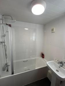 baño blanco con ducha y lavamanos en Woodhouse Apartment, en Headingley