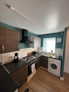 a kitchen with a stove and a washing machine at Woodhouse Apartment in Headingley