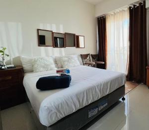 Un dormitorio con una cama grande con un bolso negro. en Inspiria Condominium Tower, beside Abreeza Ayala Mall, Davao City, en Davao City