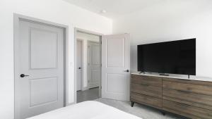een slaapkamer met een flatscreen-tv op een houten dressoir bij Landing - Modern Apartment with Amazing Amenities (ID1398X195) in Richmond