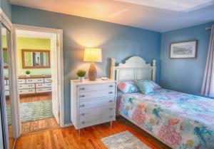 a bedroom with a bed and a dresser with a lamp at Gorgeous beach house with large pool & private beach, just 3 blocks away!! in Point Pleasant Beach