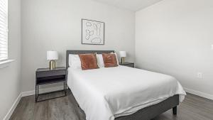 a white bedroom with a large bed with two lamps at Landing - Modern Apartment with Amazing Amenities (ID1403X426) in Houston
