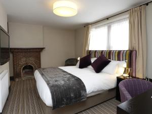 a bedroom with a large bed and a fireplace at The Red Lion Hotel in Cambridge