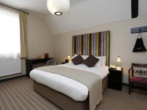 um quarto de hotel com uma cama grande e uma janela em The Red Lion Hotel em Cambridge