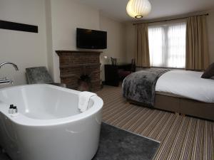 Habitación de hotel con bañera y cama en The Red Lion Hotel, en Cambridge