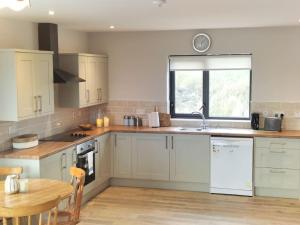 a kitchen with white cabinets and a table and a clock at Lake view Dunfanaghy in Dunfanaghy