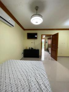 a bedroom with a white bed and a flat screen tv at Hotel PedidoSia in Higuey
