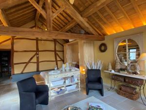un soggiorno con soffitti in legno, tavolo e sedie. di Chambre d'hôtes - Le Refuge de la Vallée a Érezée