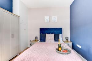 1 dormitorio con 1 cama con 1 botella de vino y fruta en Modern 1 bed close to town and station, en Worthing