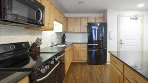 cocina con nevera negra y armarios de madera en Landing Modern Apartment with Amazing Amenities (ID2613X64) en Detroit