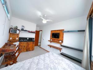 um quarto com uma cama e uma cozinha com um micro-ondas em Suíte aconchegante no Centro de Caratinga - kitnet em Caratinga