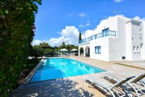 a villa with a swimming pool in front of a house at Azzurro Holiday Villas in Peyia