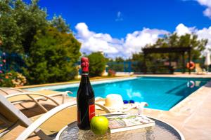 a bottle of wine sitting on a table next to a pool at Azzurro Holiday Villas in Peyia