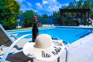 a straw hat sitting on a chair next to a bottle of wine at Azzurro Holiday Villas in Peyia