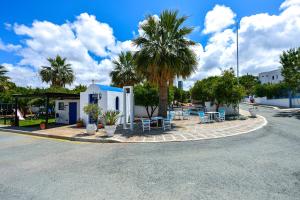 a building with chairs and palm trees on a street at Azzurro Holiday Villas in Peyia