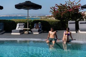 a man and a woman sitting in a swimming pool at Paros Agnanti Resort & Spa in Parikia