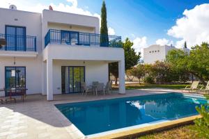 a villa with a swimming pool in front of a house at Azzurro Holiday Villas in Peyia