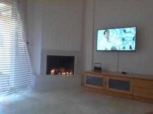 a living room with a television on a wall with a fireplace at Casa Cortijo de Calahonda in La Cala de Mijas