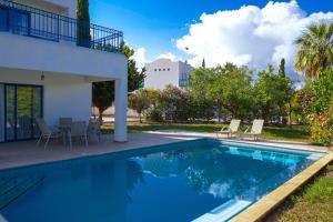a swimming pool with chairs and a house at Azzurro Holiday Villas in Peyia