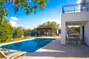 a swimming pool with a table and chairs next to a house at Azzurro Holiday Villas in Peyia