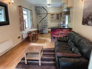 a living room with a leather couch and a table at Llangollen cosy apartment in Llangollen