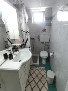 uma casa de banho branca com um lavatório e um WC em AKTIS apartment near airport em Artemida