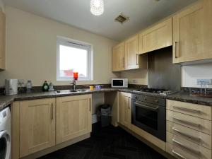 a kitchen with wooden cabinets and a sink and a window at Crownford Guesthouse - Close to Hanley centre and University in Stoke on Trent