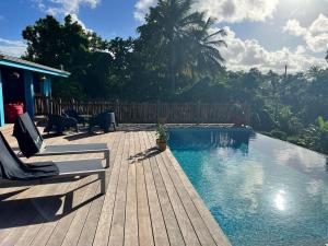 een houten terras met stoelen en een zwembad bij Maison de 3 chambres avec piscine privee terrasse et wifi a Sainte Anne a 9 km de la plage in Sainte-Anne