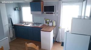 a kitchen with blue cabinets and a white refrigerator at Bungalow île D'oleron in La Cotinière