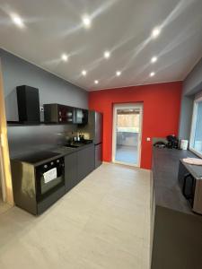 a large kitchen with red walls and black counters at K71 Guest House in Fertőd