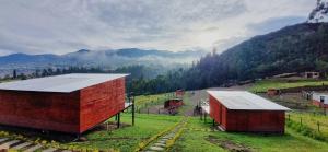 a couple of barns in a field with mountains at NaturaLove Glamping Mongui in Monguí
