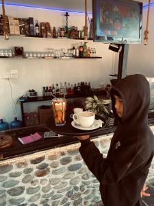 una persona sosteniendo una bandeja con una taza de café en Aati cafe en Pokhara