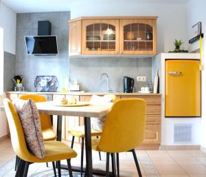uma cozinha com uma mesa e cadeiras amarelas em Rosenwinkel Maisonettewohnung DG em Halberstadt