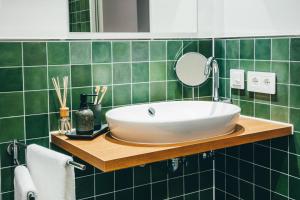 ein grün gefliestes Bad mit einem Waschbecken und einem Spiegel in der Unterkunft LIVELY Weiße Dame Gronau in Gronau