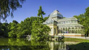 einen Wintergarten in einem Park neben einem See in der Unterkunft voco Madrid Retiro, an IHG Hotel in Madrid