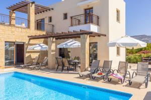 een villa met een zwembad met stoelen en parasols bij Villa Michael Coral in Peyia