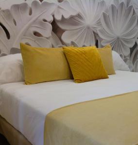a white bed with two yellow pillows on it at Serendipity Hispalis Nervión in Seville