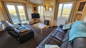 a living room with a leather couch and a tv at Penmor in Bude