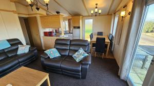 a living room with a couch and a table and a kitchen at Penmor in Bude