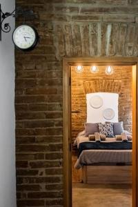 a bedroom with a brick wall and a clock on the wall at Casa da Travessa - Lago do Alqueva in São Marcos do Campo