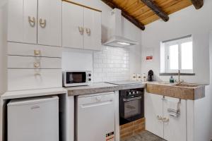 a white kitchen with white cabinets and a sink at Casa da Travessa - Lago do Alqueva in São Marcos do Campo +7 photos