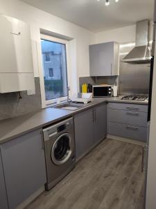 a kitchen with a sink and a washing machine at Taigh Shen in Stornoway