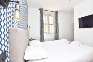 a bedroom with a white bed and a tv at Renovated 2BD apartment in Parc Belleville in Paris