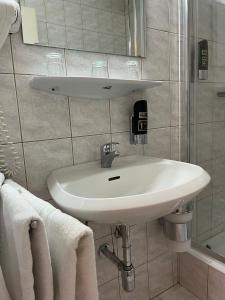 La salle de bains est pourvue d'un lavabo, d'un miroir et de serviettes. dans l'établissement City Hotel Post 12, à Braunau am Inn