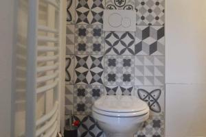 a bathroom with a toilet and a tiled wall at Suites Rive Gauche - FONTAINEBLEAU - Chez Andrea in Fontainebleau