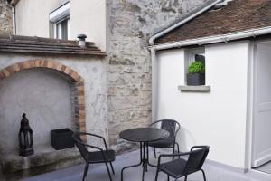 a patio with chairs and a table and a fireplace at Suites Rive Gauche - FONTAINEBLEAU - Chez Andrea in Fontainebleau