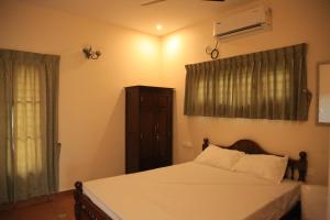 a bedroom with a bed with white sheets and a window at Ponni Homestay Kumbakonam in Kumbakonam